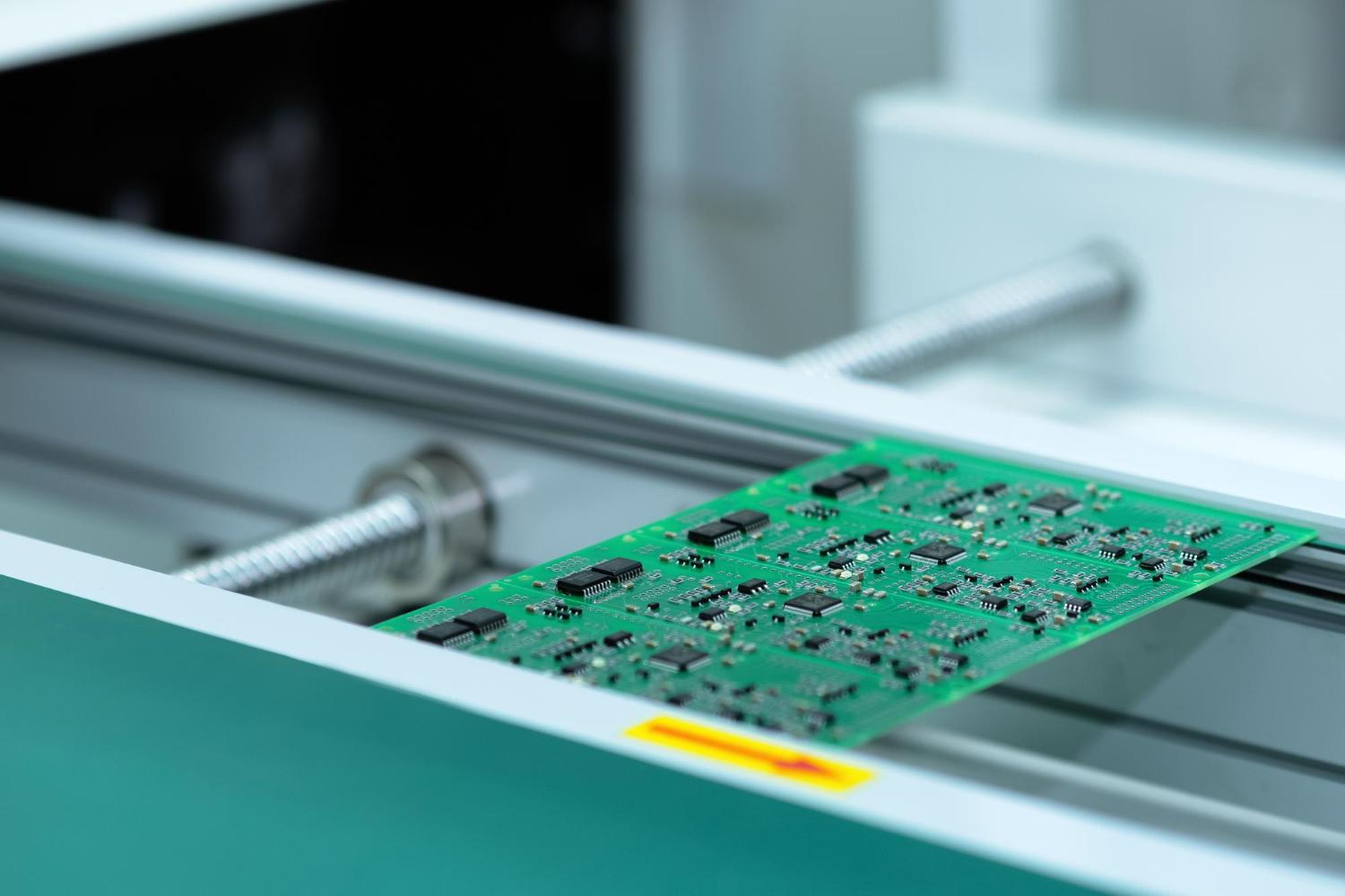 Printed circuit board moving through automated manufacturing equipment