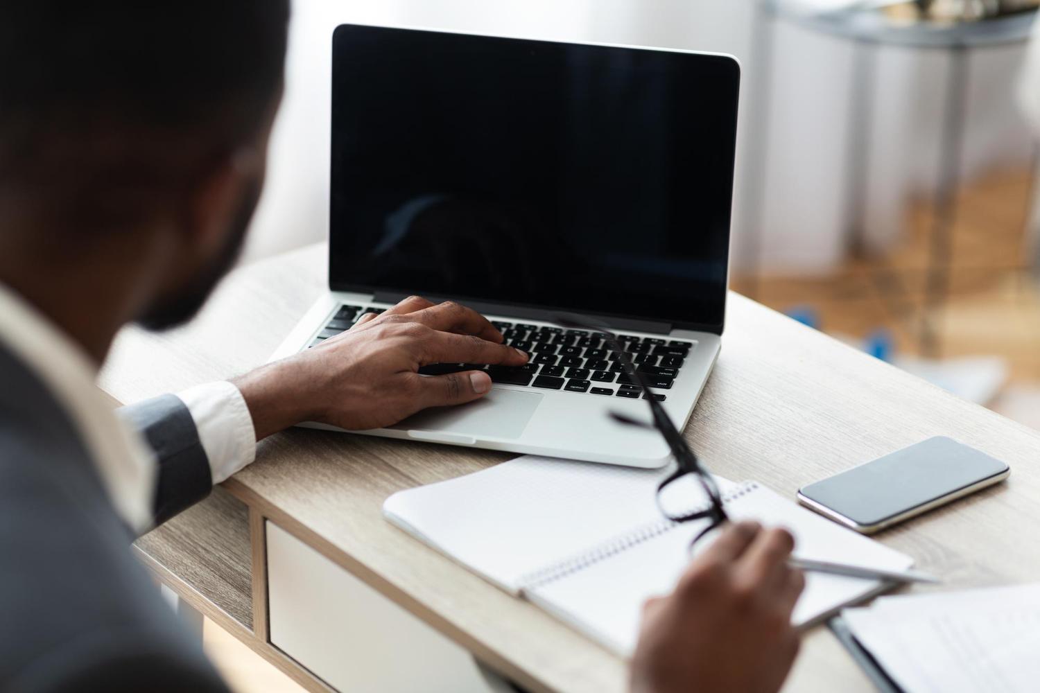 Person evaluating a laptop while taking written notes