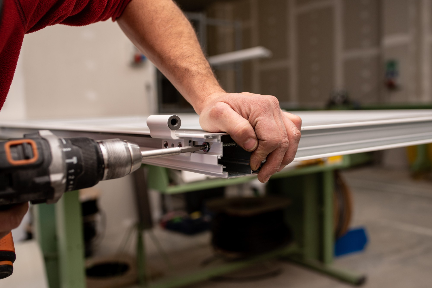 Worker fastening hardware to a metal frame profile