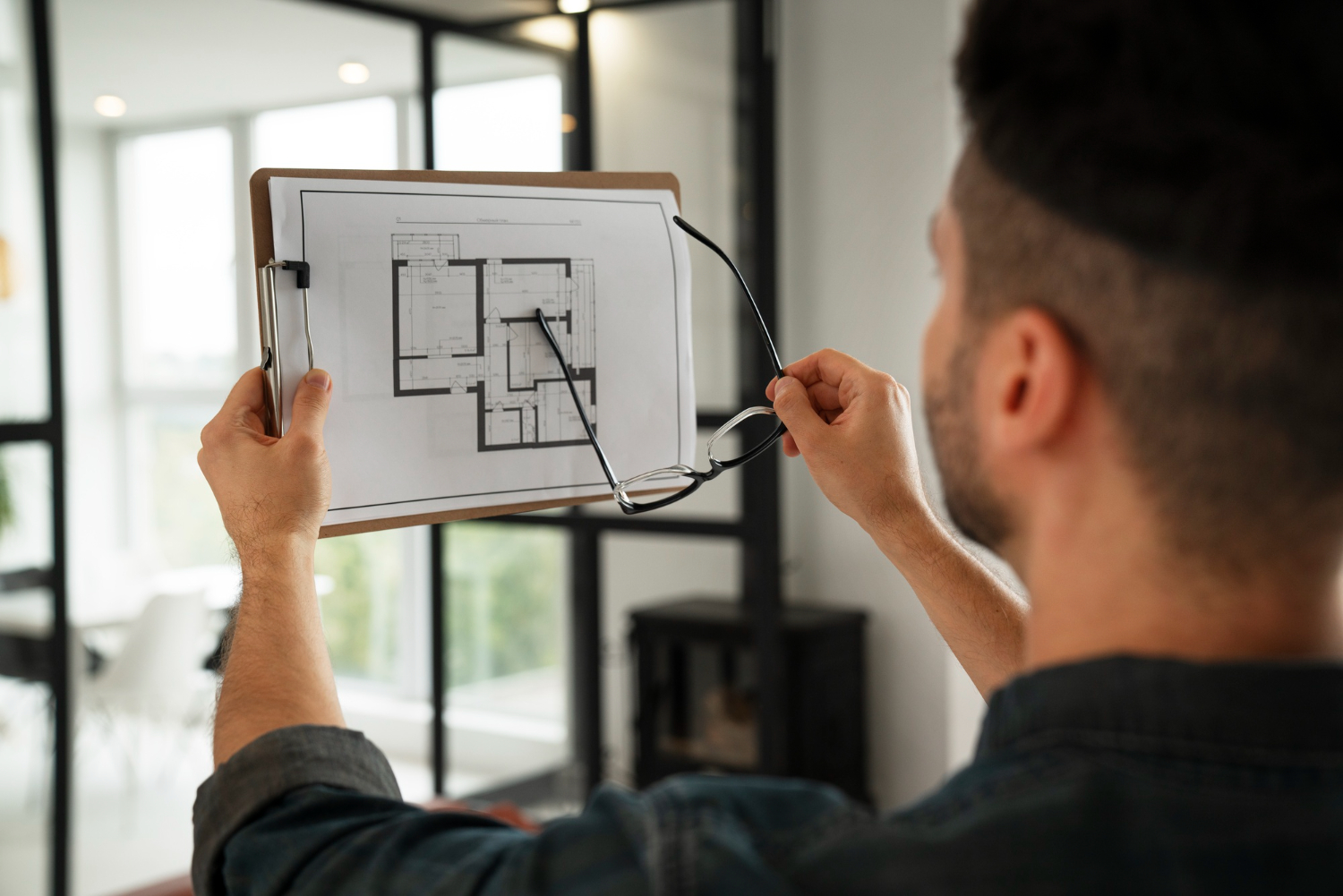 Person reviewing a floor plan beside a glazed interior partition