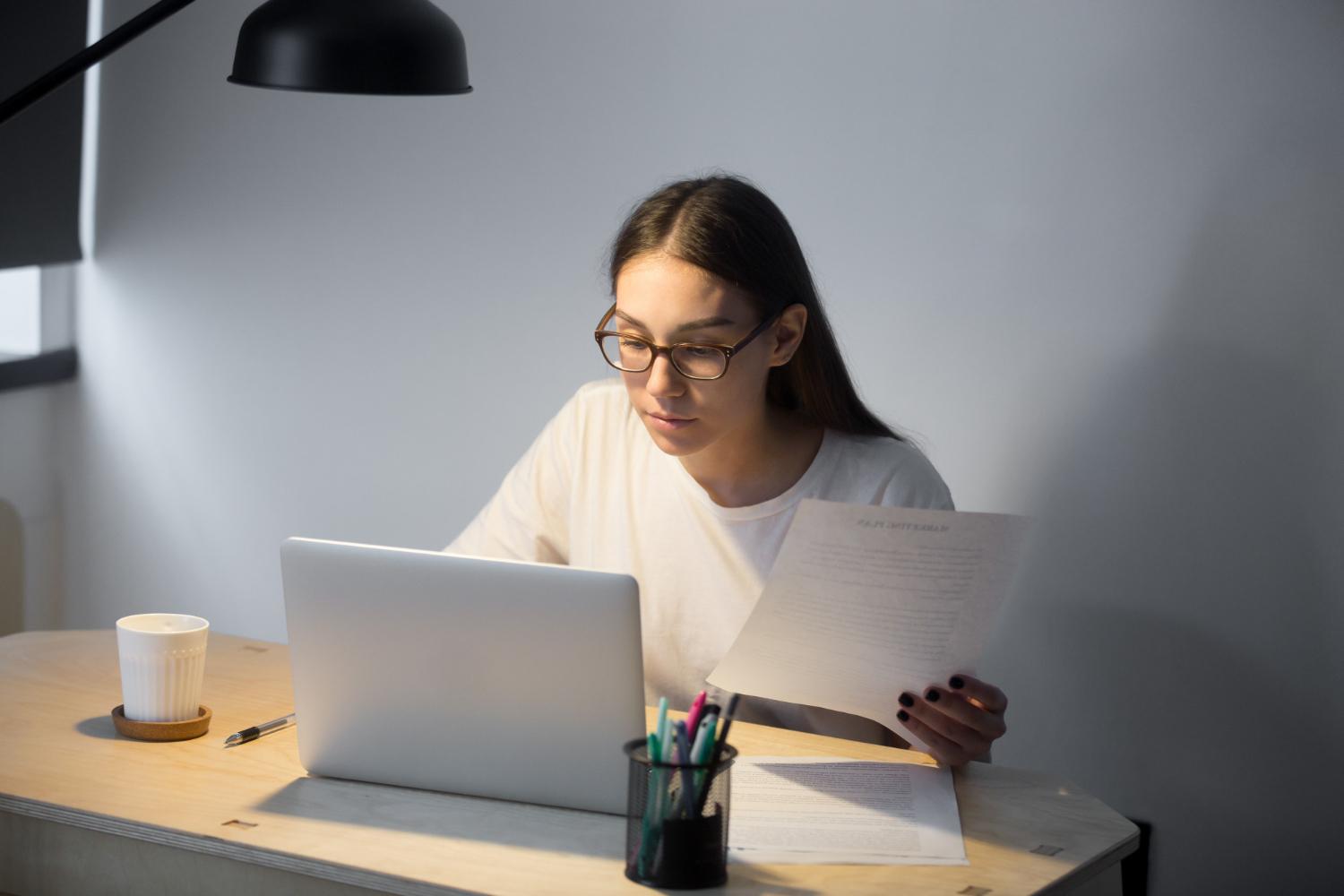 Student reviewing documents while working on a laptop