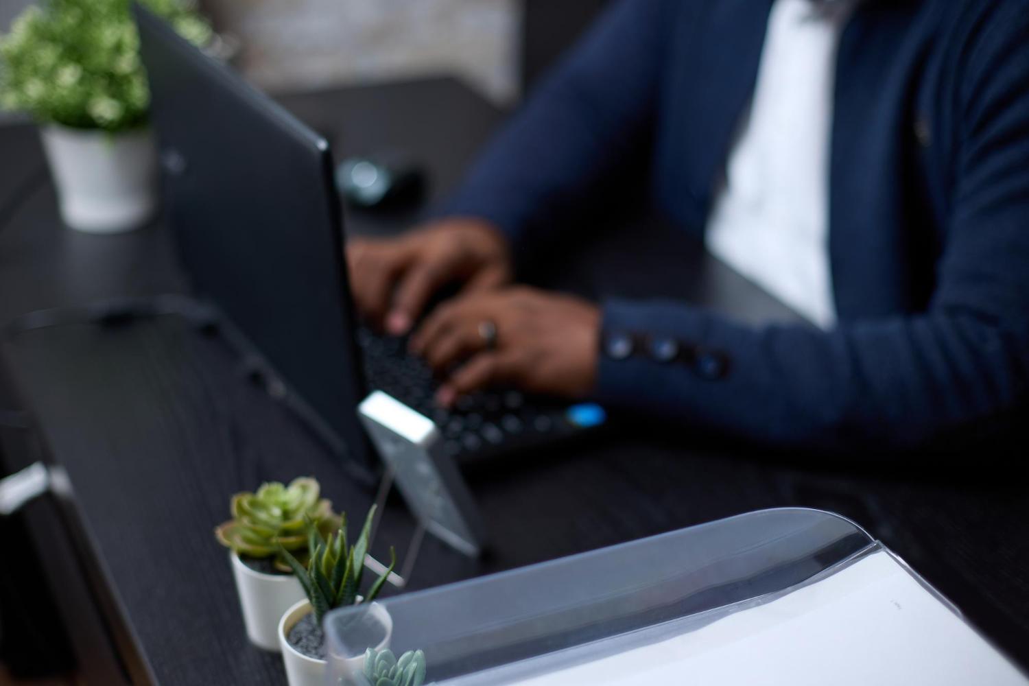 Professional using a black business laptop at an office desk
