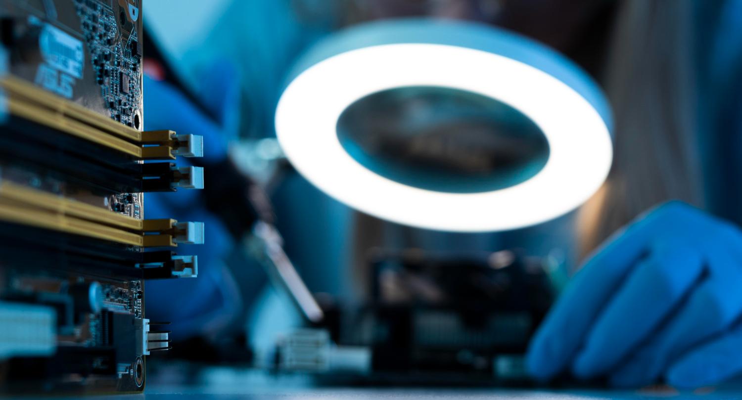 Technician visually inspecting an electronic component under a ring light