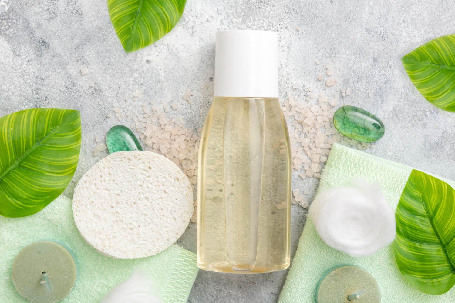 Unbranded personal care bottle arranged with botanical leaves and bath accessories