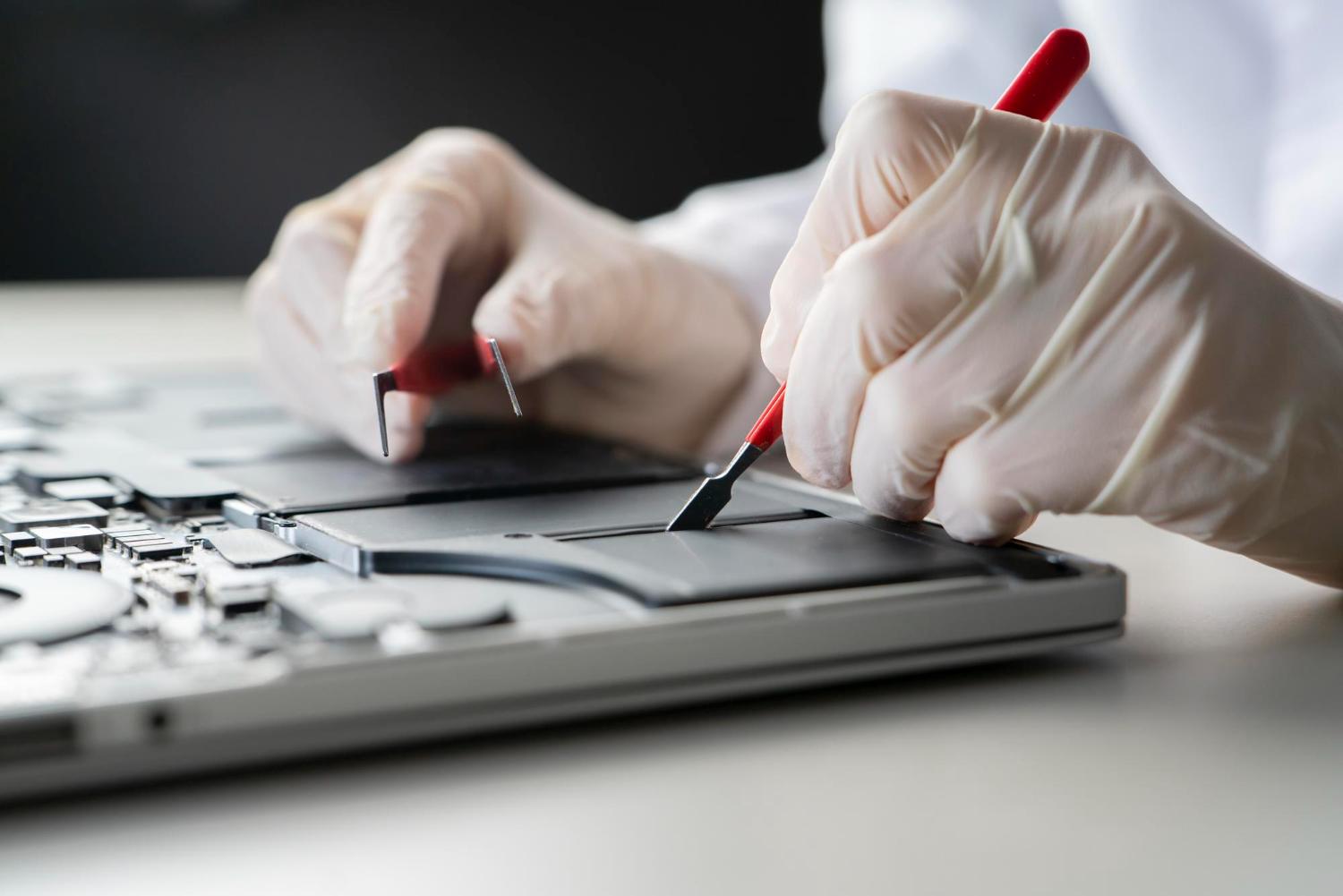 Technician examining internal components of an opened laptop