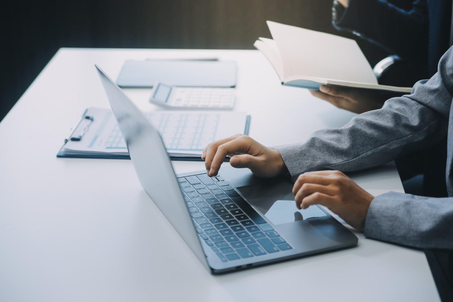 Professional researching service information with a laptop and reference book