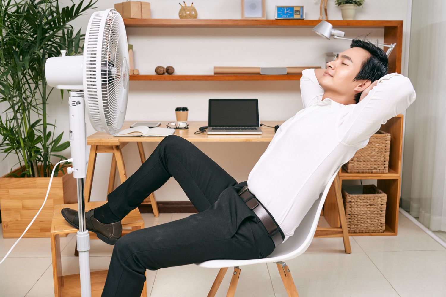 Person using a portable stand fan in a bright home office